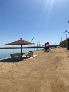 an empty beach with an umbrella and a playground at Hotel & Resort Golden Marina Yanbu in Yanbu