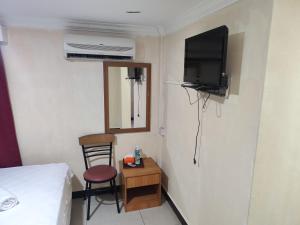 a small room with a bed and a chair and a television at Wings Grand Orchard Hotel in Kuala Lumpur