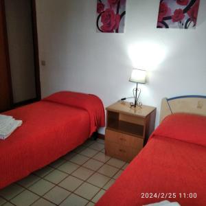 Habitación con 2 camas y mesa con lámpara. en casale guidaloca, en Castellammare del Golfo