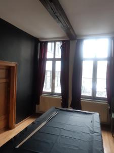 a bed in a room with two windows at Chambres d'Hôte Alarome in Huy