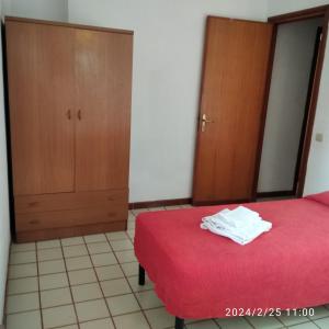 1 dormitorio con cama roja y armarios de madera en casale guidaloca, en Castellammare del Golfo