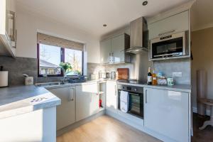 a kitchen with white cabinets and a large window at The Bothy, Landrake in Saltash