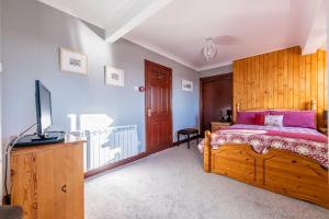 a bedroom with a bed and a flat screen tv at The Bothy, Landrake in Saltash