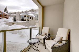 two chairs and a table on a balcony with snow at Slopes_loft in Brian Head