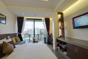 a bedroom with a large bed and a tv at Solitaire Damnak Villa Hotel in Siem Reap