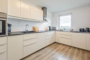 a white kitchen with white cabinets and a window at Roof-Suite 01 I Aufzug I BBQ I WiFi I Balkon I TV in Rheda-Wiedenbrück +17 photos