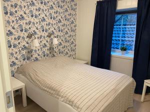 uma cama num quarto com papel de parede azul e branco em Rosendal Apartments Motellet em Rosendal