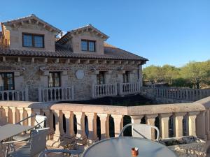 a house with a balcony with tables and chairs at Hotel Rural El Cañón del Duratón in Sepúlveda
