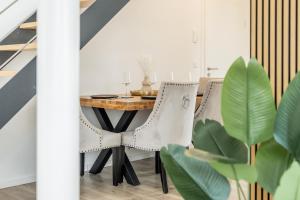a dining room with white chairs and a wooden table at Roof-Suite 01 I Aufzug I BBQ I WiFi I Balkon I TV in Rheda-Wiedenbrück
