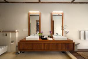 a bathroom with two sinks and two mirrors at Dickwella Resort and Spa in Dickwella