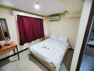 ein Schlafzimmer mit einem Bett mit einem roten Vorhang in der Unterkunft Wings Grand Orchard Hotel in Kuala Lumpur