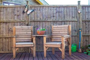 two chairs and a table on a patio with a fence at Wheel Cottage, Landrake in Saltash