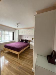 - une chambre avec un lit violet et une fenêtre dans l'établissement Stylish 3 Bedroom House Basildon/Essex Upto 5 Guests, à Basildon