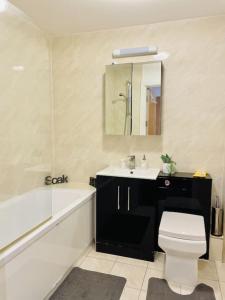a bathroom with a tub and a toilet and a sink at Stylish 3 Bedroom House Basildon/Essex Upto 5 Guests in Basildon