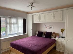 1 dormitorio con cama morada y ventana en Stylish 3 Bedroom House Basildon/Essex Upto 5 Guests, en Basildon
