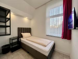 um pequeno quarto com uma cama e uma janela em Durmaz Hotel em Hanôver