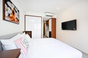 a bedroom with a white bed with a television on the wall at Saigon Hotel & Apartment in Ho Chi Minh City