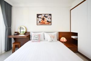 Schlafzimmer mit einem weißen Bett und einem Schreibtisch in der Unterkunft Saigon Hotel & Apartment in Ho-Chi-Minh-Stadt