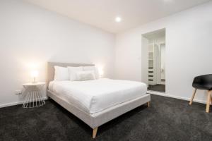 1 dormitorio blanco con 1 cama y 1 silla en Central & Modern Inner City Apartment with Wi-Fi, en Launceston