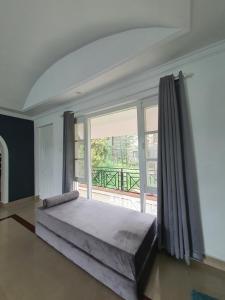 a bedroom with a large bed and a large window at The Cocoon Project in McLeod Ganj