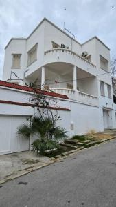 a white building with a tree in front of it at Nomads Hostel Tunisia in Tunis