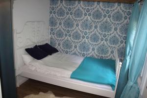 a small white bed with blue pillows on it at Blockhouse Nicks Lodge in Hatten