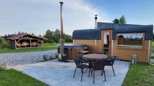 a small cabin with a table and chairs and a barbecue at Sila terases in Madona