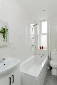 a white bathroom with a tub and a toilet at Stunning studio flat in the heart of Brighton in Brighton & Hove