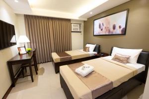 a hotel room with two beds and a desk at Soleil Suites Cebu in Cebu City