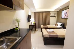 a kitchen with two beds and a sink in a room at Soleil Suites Cebu in Cebu City