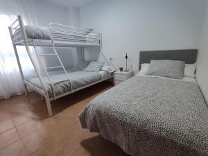 a bedroom with a bunk bed and a bed and a chair at Apartamento en Sevilla con piscina y parking in La Algaba