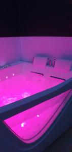 een bed met roze verlichting op een kamer bij La Vallée Douce 