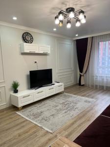 un salon avec une télévision à écran plat sur une armoire blanche dans l'établissement ЖК Lake town 3, à Almaty