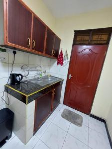 a small kitchen with a red door and a counter at Roma Stays - Budget Studio in Busia (Opp Shell petrol Station) in Busia