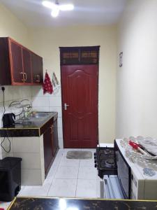 a kitchen with a red door in a room at Roma Stays - Budget Studio in Busia (Opp Shell petrol Station) in Busia