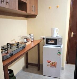 a kitchen with a stove and a refrigerator with a microwave at Roma Stays - Budget Studio in Busia (Opp Shell petrol Station) in Busia