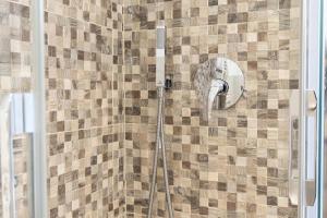 una ducha con cabezal de ducha en una pared de azulejos en Guest House DOLCE LAGUNA 2 en Tessera