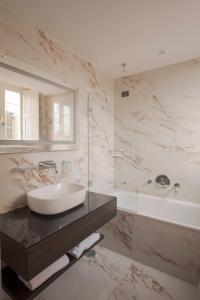 uma casa de banho com um lavatório, uma banheira e um espelho. em Hotel Viminale em Roma