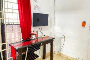 un escritorio con un ordenador con una cortina roja en RedDoorz Syariah Near Balai Meuseuraya Aceh en Lamnyong
