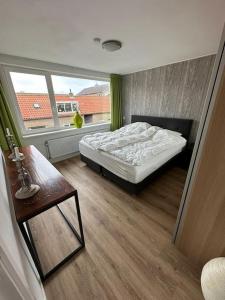 een slaapkamer met een bed, een tafel en een raam bij 'Nieuw' Strand 83 - Family house in Egmond aan Zee
