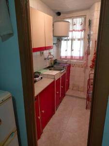 a small kitchen with red cabinets and a window at Apartamento Casco Viejo in Ourense +3 photos