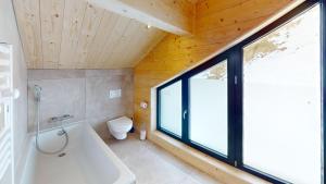 a bathroom with a tub and a toilet and a window at Chalet Folie in Peisey-Nancroix