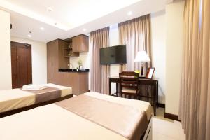 a hotel room with two beds and a desk at Soleil Suites Cebu in Cebu City