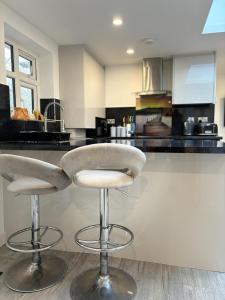 a kitchen with two bar stools in front of a counter at Cozy 2 Bed Property in High Wycombe Tn in High Wycombe