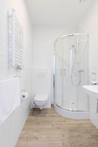 a white bathroom with a shower and a toilet at Zefiro Na Gnilnej in Gdańsk