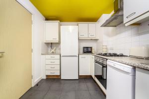 a kitchen with white appliances and a yellow ceiling at The Whitecross Street Apartment in London