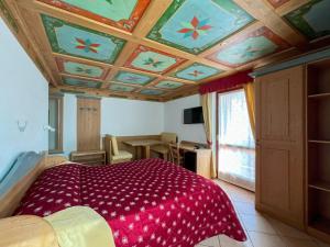 a bedroom with a red comforter on the ceiling at Hotel Residence Dahu in Passo del Tonale