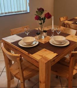 a wooden table with two plates and a candle on it at OR Tambo Int Airport Rudman B Self Catering Two Bedroom Home in Boksburg