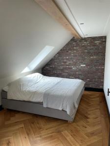 Cama en habitación con pared de ladrillo en B&B Il Settimo Cielo, en Someren