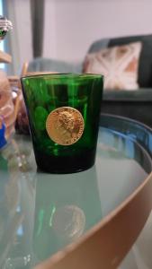 a green cup with a coin on a glass table at ESCAL'HOME appart design au pied de l'aéroport, parkings in Blagnac